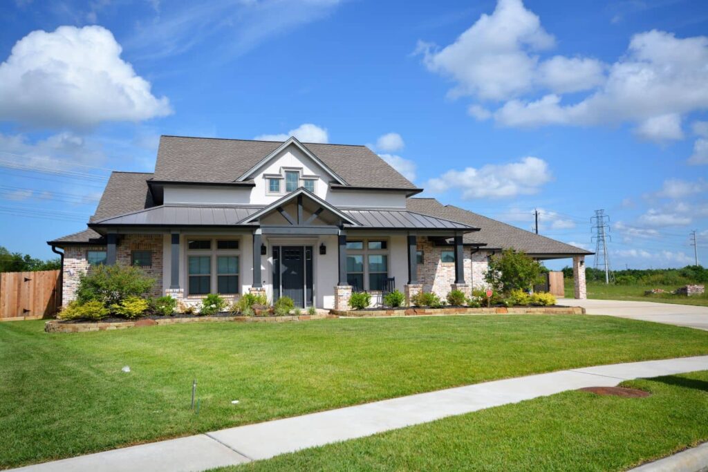 A modern suburban house with a well-maintained lawn under a blue sky.